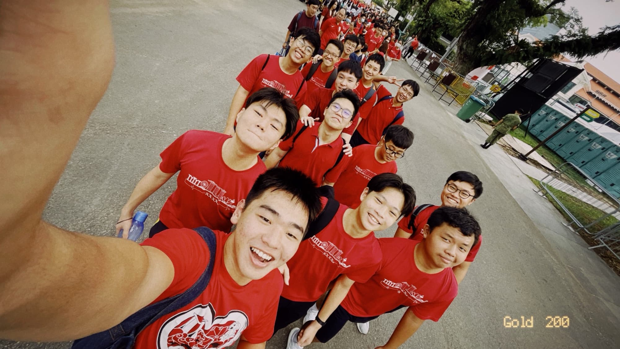 A group of smiling ASEAN Academy students in matching red shirts taking a selfie together